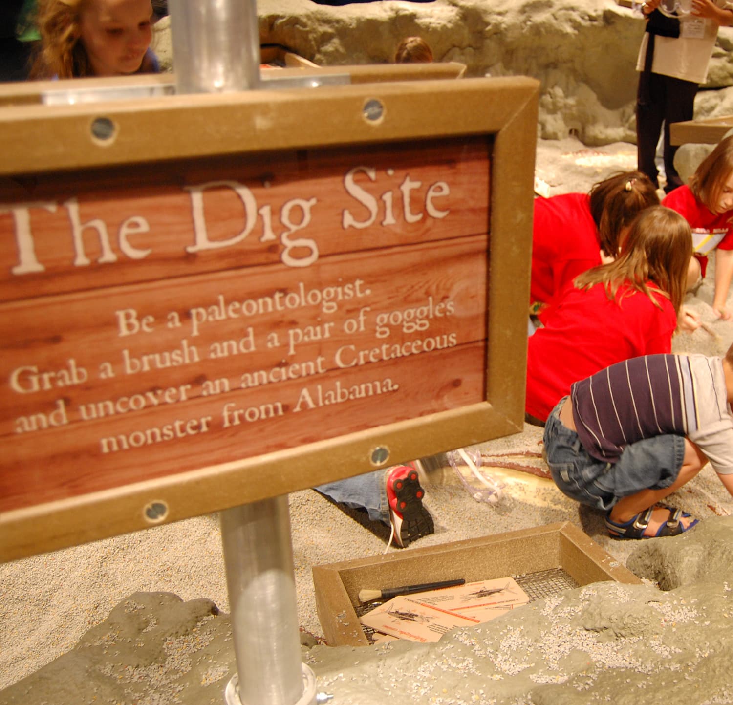 Kids excavate fossils at The Dig Site, a hands-on paleontology exhibit at a children's science center.
